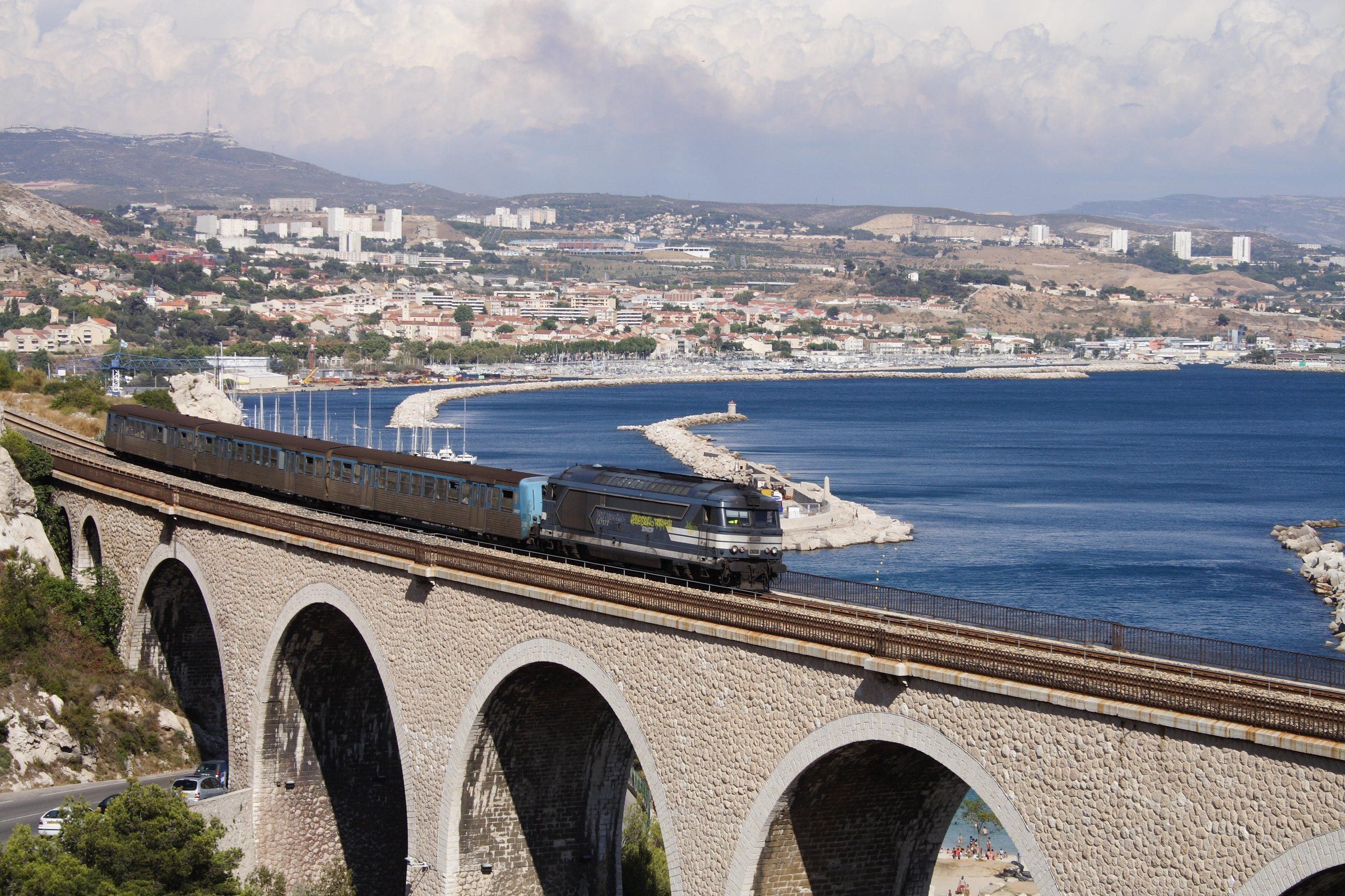 Le train de la Côte Bleue sur un viaduc au-dessus de L'Estaque, face à la rade de Marseille